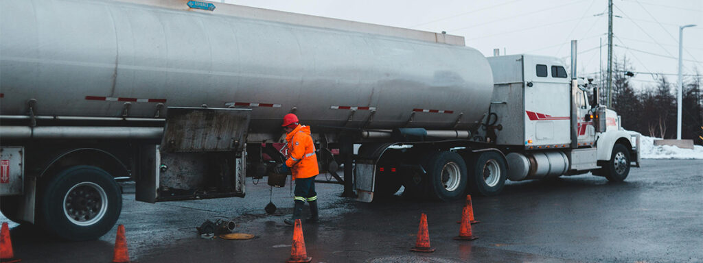 workman cleaning compartment of cargo tanker on city road